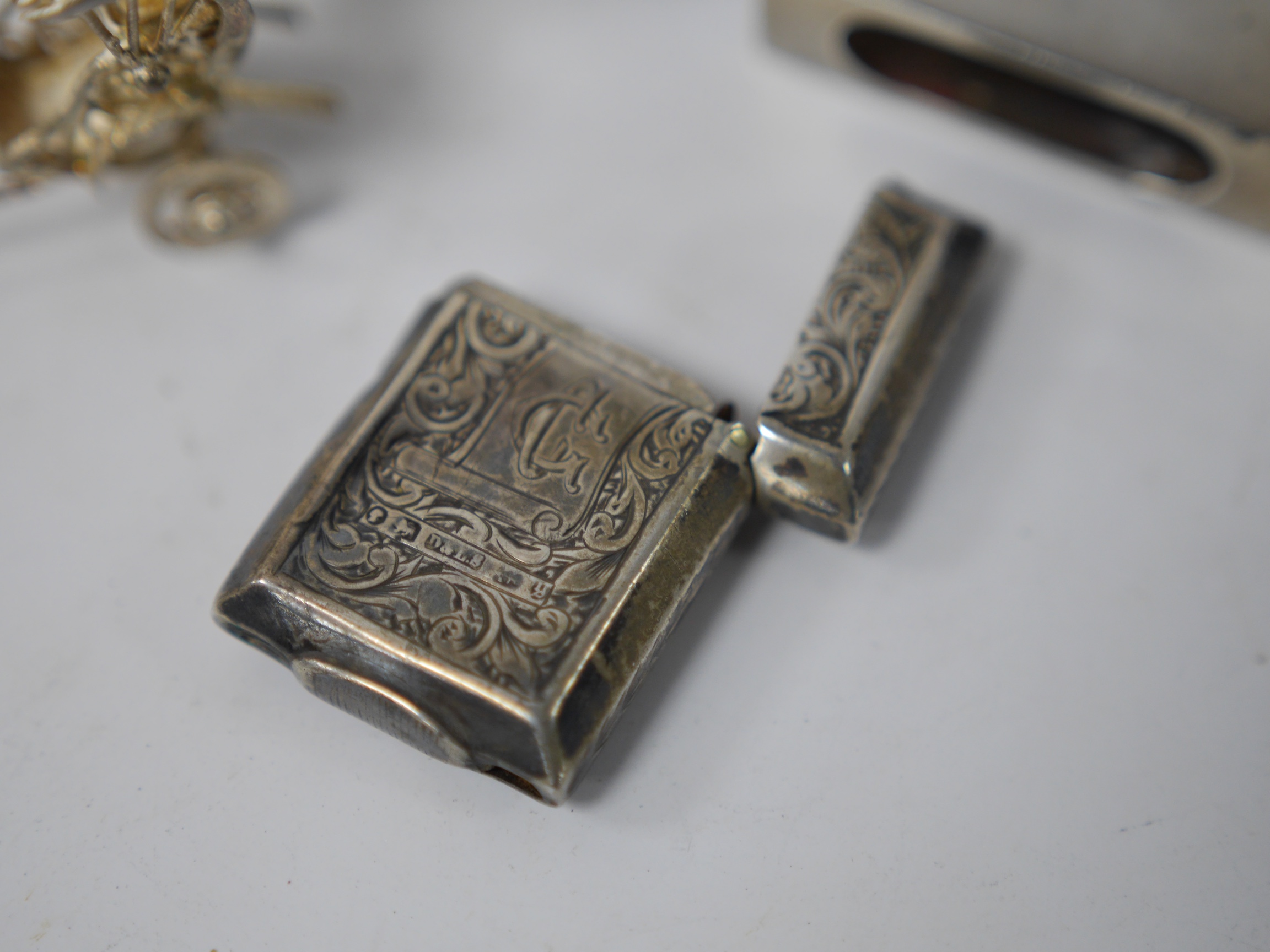 Assorted small collectables including a late Victorian silver vesta case, Birmingham, 1898, a small silver mounted circular photograph frame, a silver mounted glass pot and cover, a silver matchbox sleeve and three other